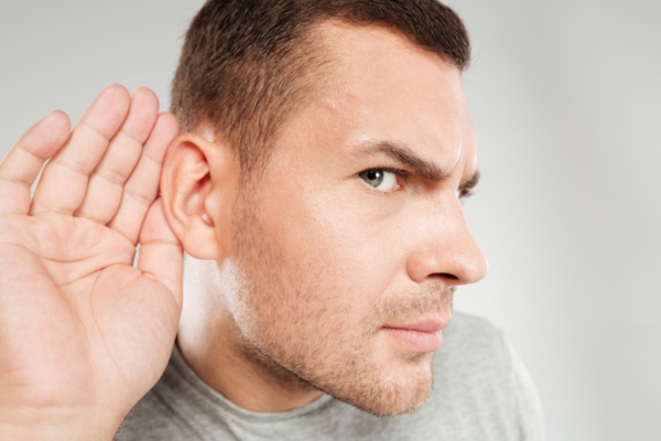 man with hand on ear listening to whistling sound